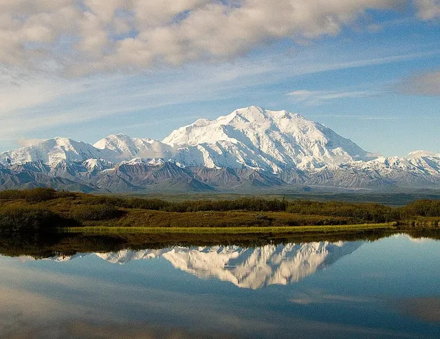 Denali's snow-covered massif rising above green tundra and the Alaska Range