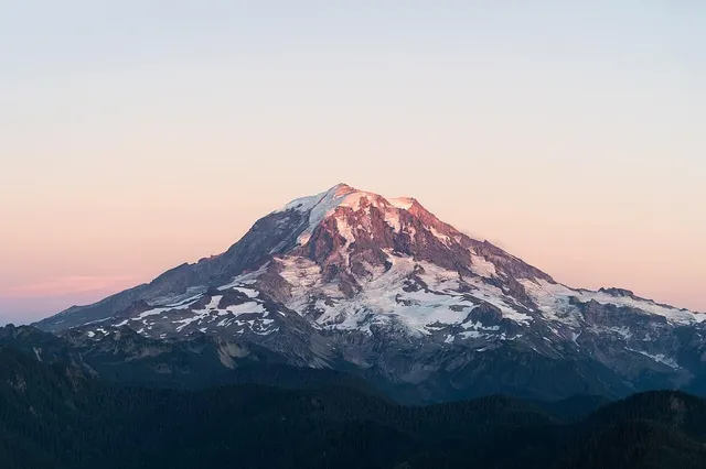 Glacier-covered cone of Mount Rainier rising above forested foothills