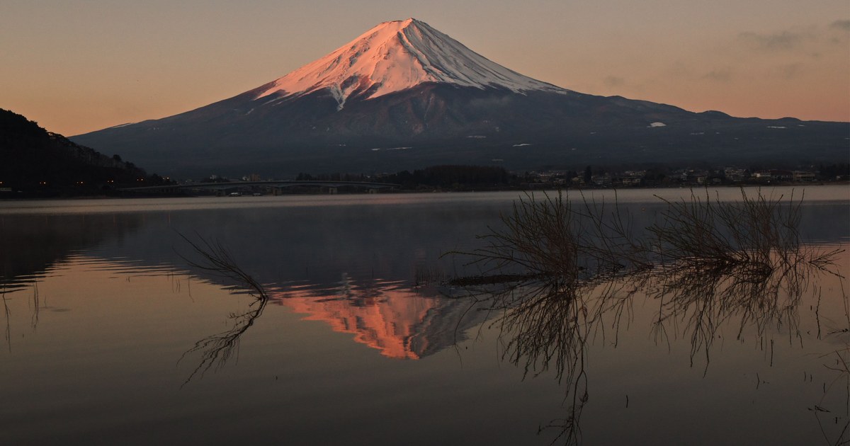 Mount Fuji at dawn from Lake Kawaguchiko, pink first light on the summit reflected in still water