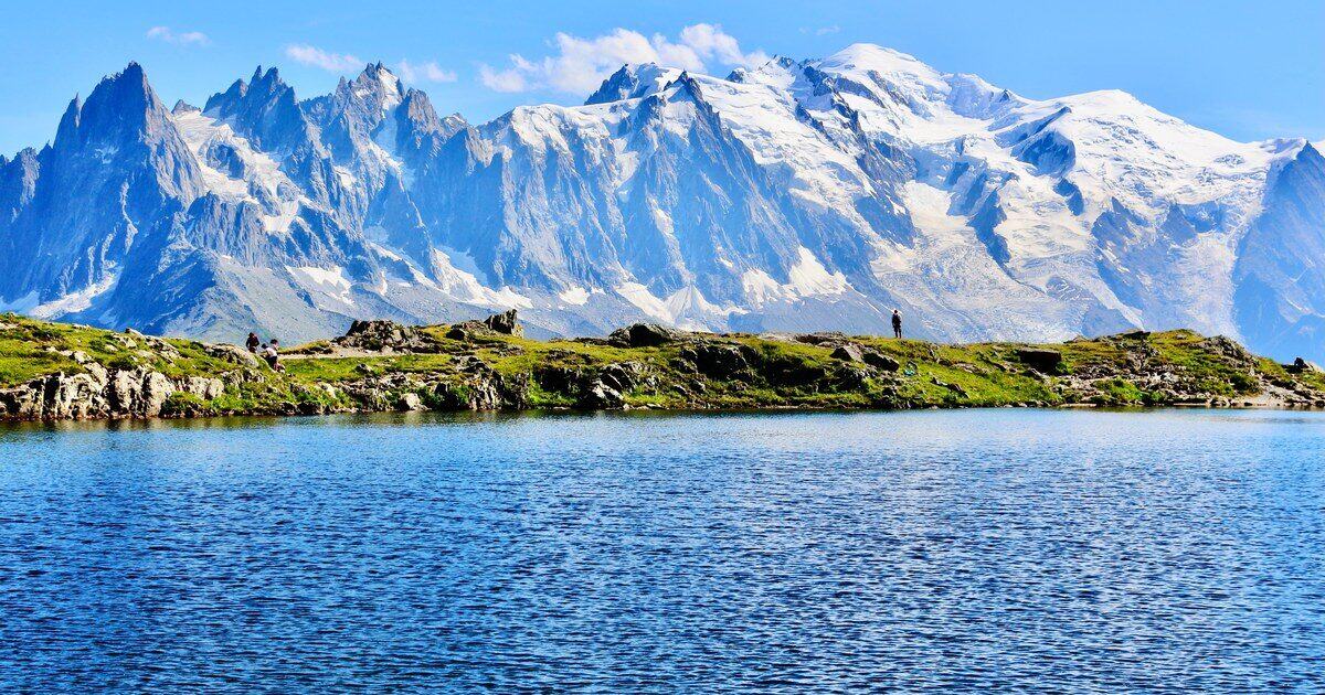 Snowy Alpine peaks and granite spires reflected in a clear blue mountain lake