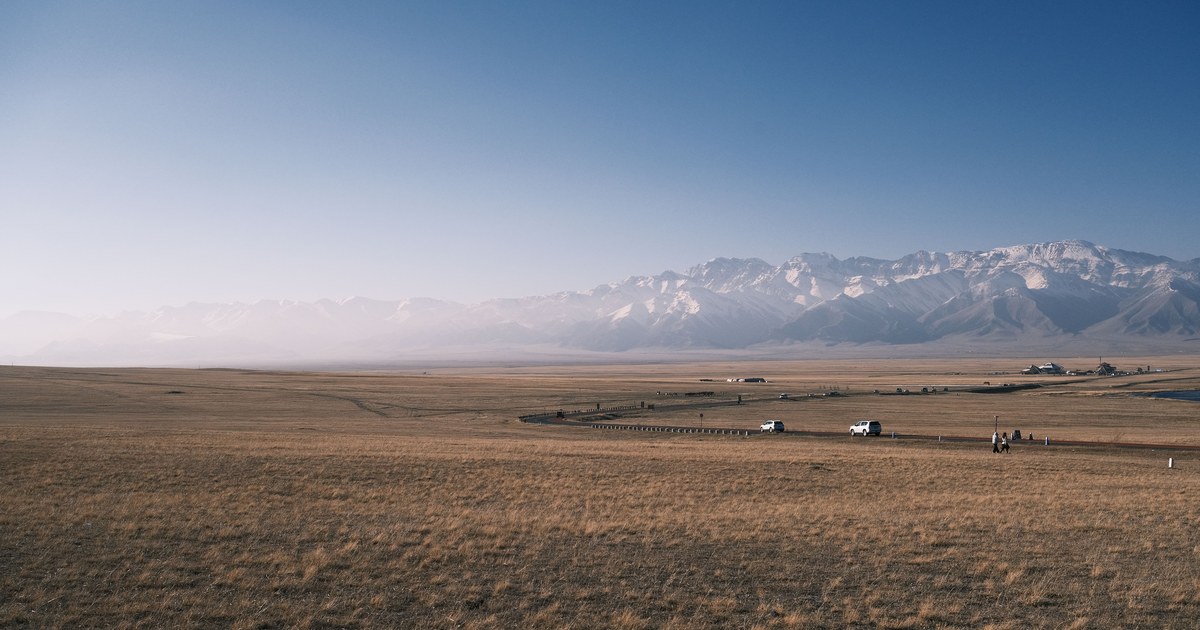 A distant snow-capped range floating in haze on the far horizon above a wide plain