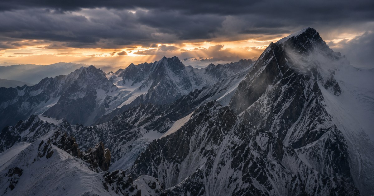A stark, steep-sided snow pyramid wrapped in wind-torn cloud under a hard blue sky