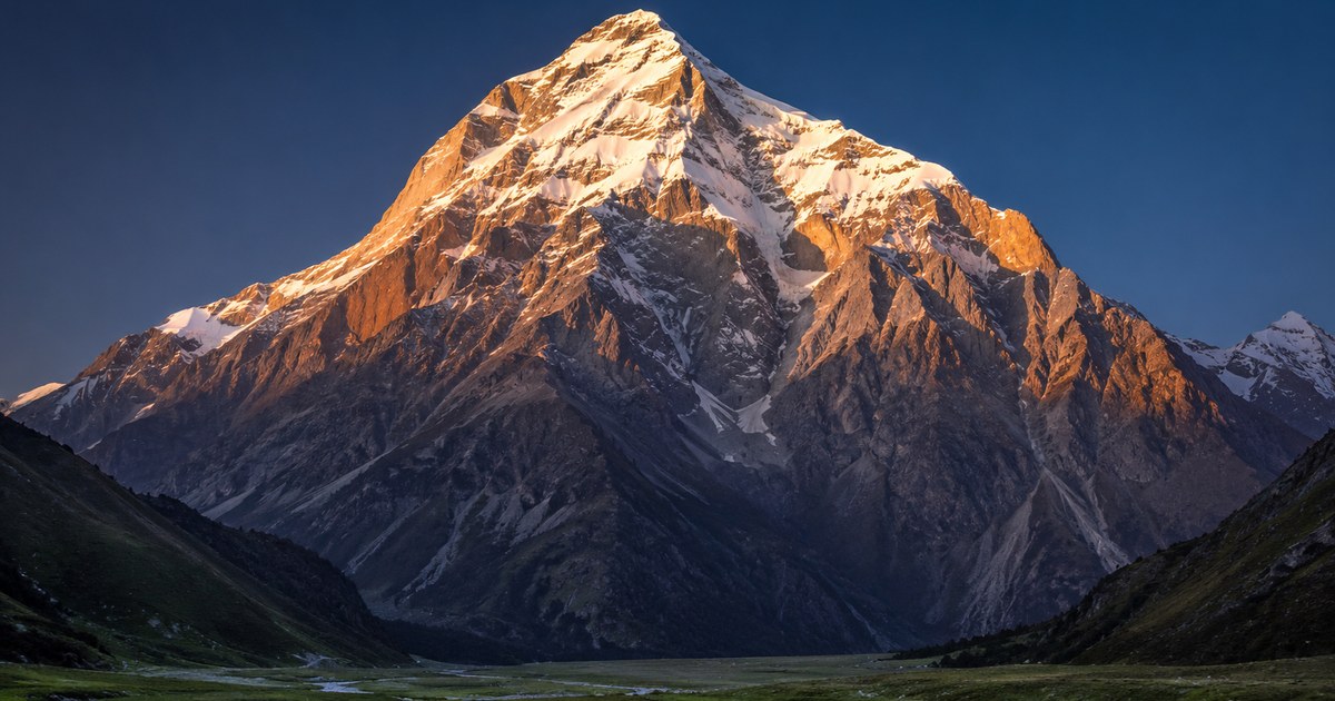 A massive snow-covered mountain rising in one sweep from low tundra to a high summit