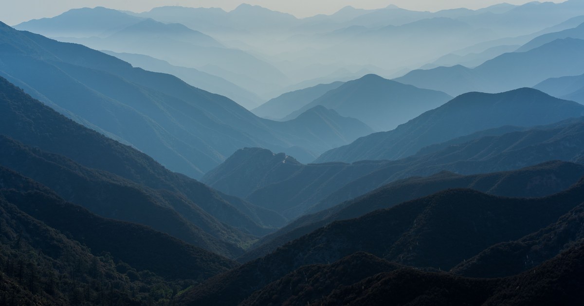 Layered mountain ridges fading from dark green to pale blue with distance